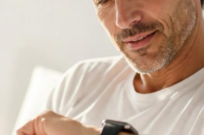 Homme au réveil qui regarde sa montre intelligente, dans une chambre lumineuse